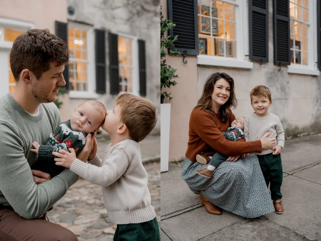 During charming Charleston mini sessions, a family of four poses outdoors near a building with large windows. In the first image, a man holds a baby while a toddler kisses the baby's head. In the second image, a woman crouches, hugging the baby and toddler as they both smile toward the camera.